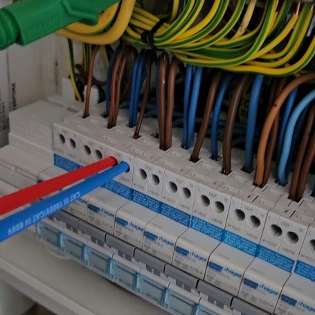 A consumer unit with brown, blue and green-and-yellow cables dressed into the breakers