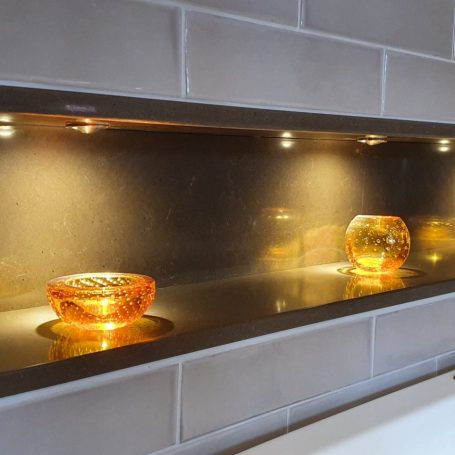 Warm downlights set into a tiled recess, lighting two amber glass bowls