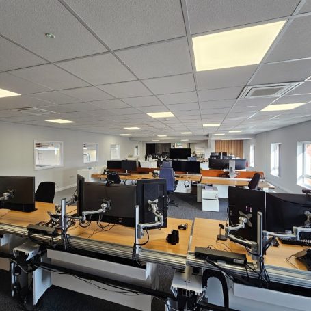 An open-plan office lit by ceiling light panels
