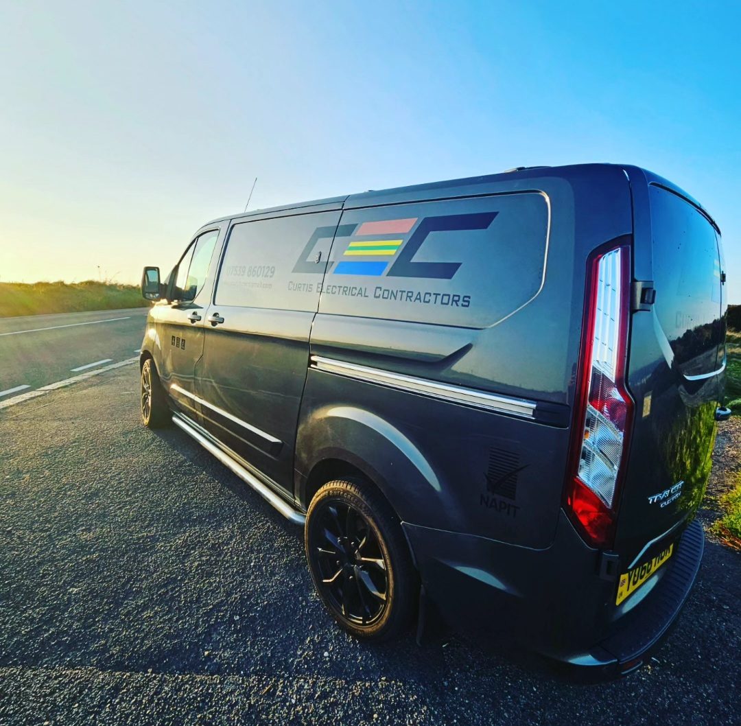 The Curtis Electrical Contractors van, in its grey CEC livery with the brown, green-and-yellow and blue stripes, parked at the roadside in low evening sun